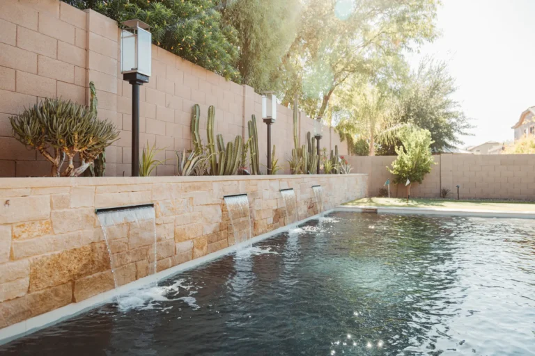 Clean backyard pool with a stone water feature wall