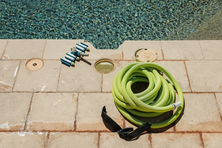Pool cleaning hose and tools on a pool deck