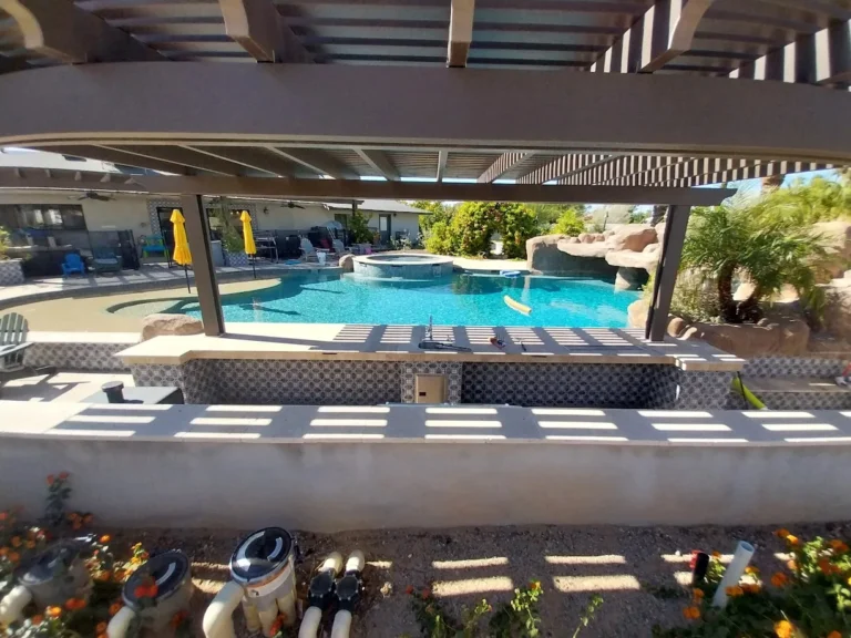 Completed pool remodel beneath a shade pergola